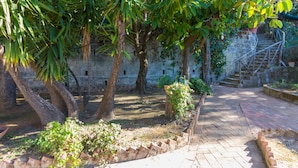 A courtyard with trees, a brick pathway, and a stone wall.