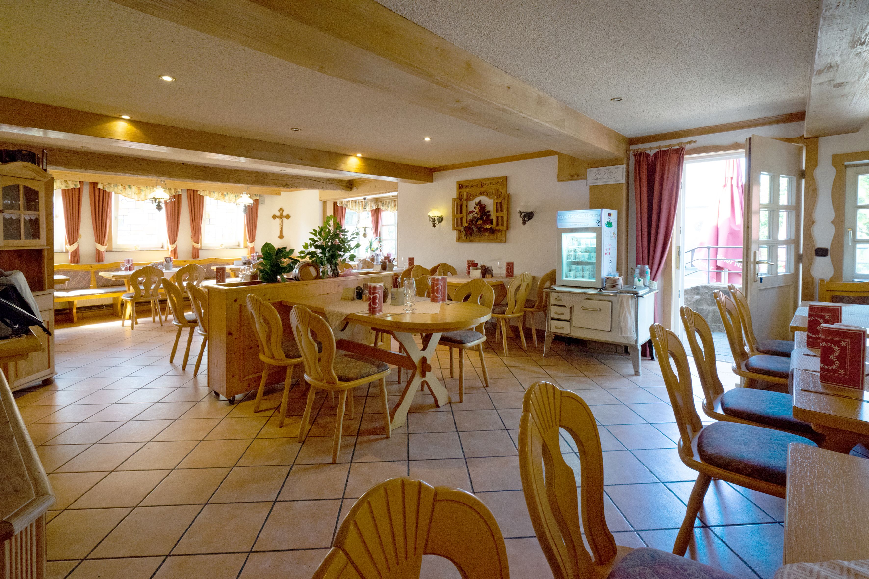 A dining area with wooden furniture, a large table, and a cross on the wall.