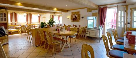 A dining area with wooden furniture, a large table, and a cross on the wall.