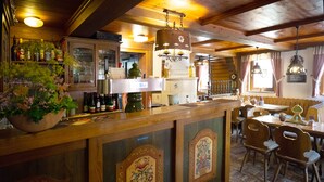 Un rústico bar con decoración de madera, una barra llena de botellas y un comedor con sillas y una mesa.