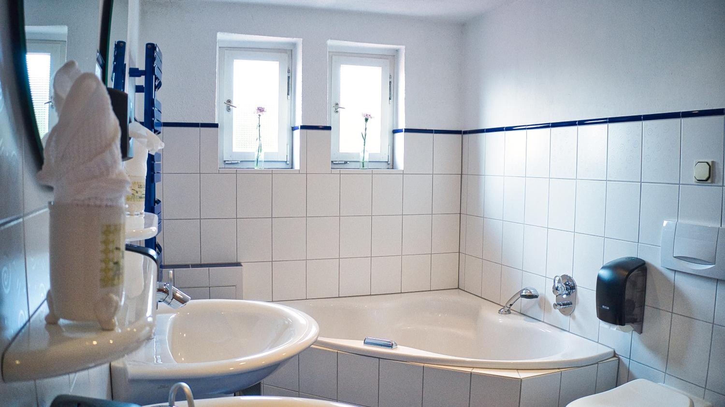 A bathroom with a bathtub, two sinks, and a window.