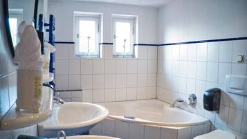 A bathroom with a bathtub, two sinks, and a window.