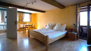 Un dormitorio con una cama de madera, una mesita de noche pequeña, una silla y una mesa de comedor con sillas.