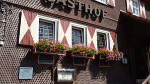 Un edificio con un letrero que dice "CASTHOF" y macetas con flores sobre las ventanas.
