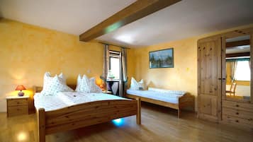 A room with two wooden beds, a nightstand with a lamp, a wooden wardrobe, and a painting on the wall.