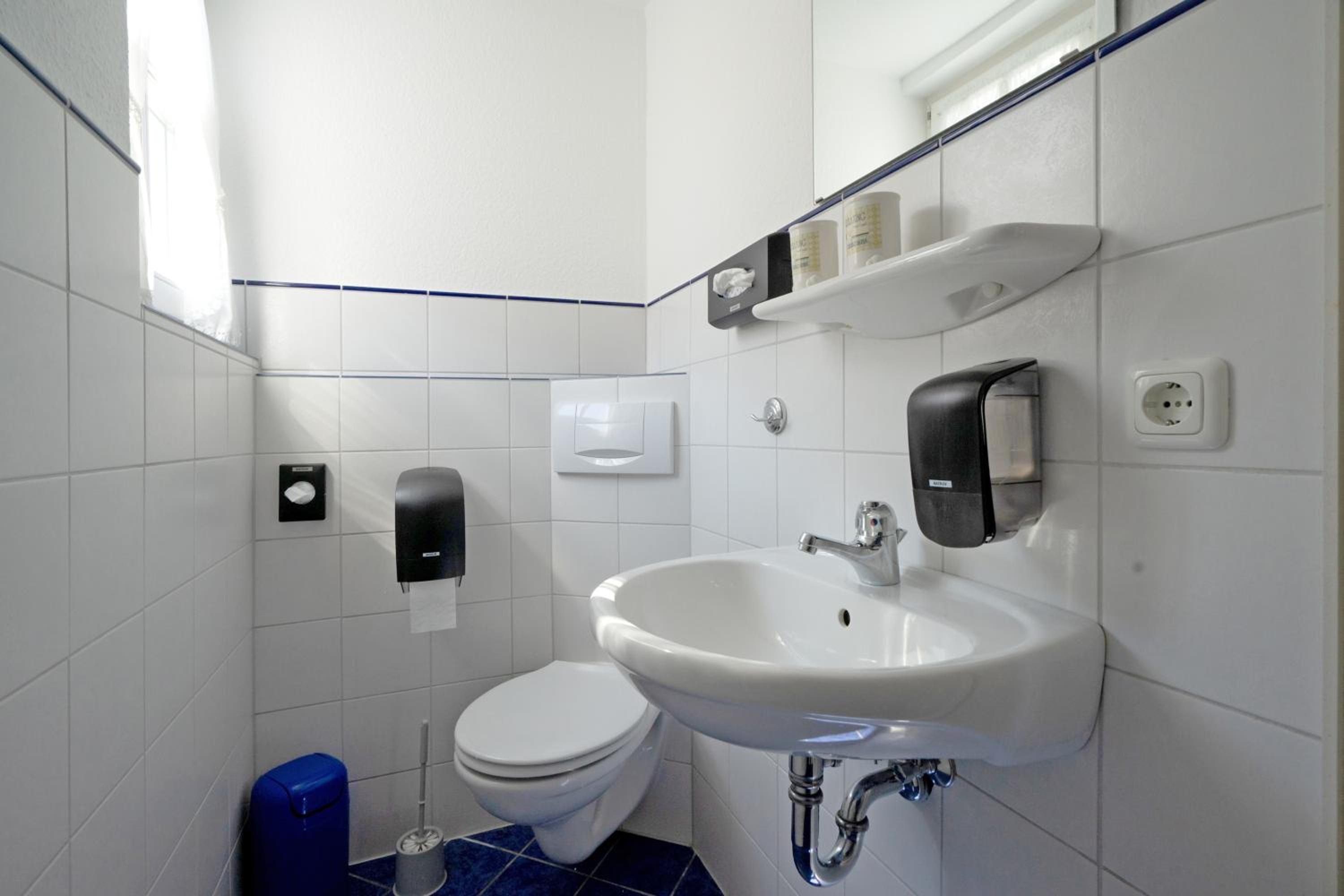 Un baño moderno con un lavabo, inodoro y secador de manos blanco.