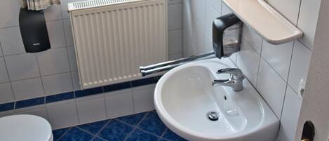 A bathroom with a white sink, a mirror, and a window with curtains.