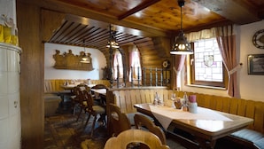 Un restaurante con mobiliario de madera, suelo de baldosas y una ventana con vitrales.