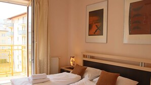 A hotel room with two beds, a nightstand with a lamp, a framed picture on the wall, and a view of the outside balcony. - Bryza (CH18B) - CH18B (Swinoujscie)