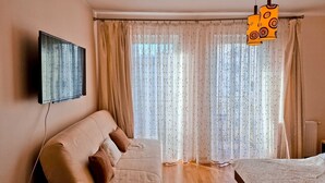 A room with a sofa, a bed, a TV mounted on the wall, and a window with curtains. - Bryza (CH18B) - CH18B (Swinoujscie)