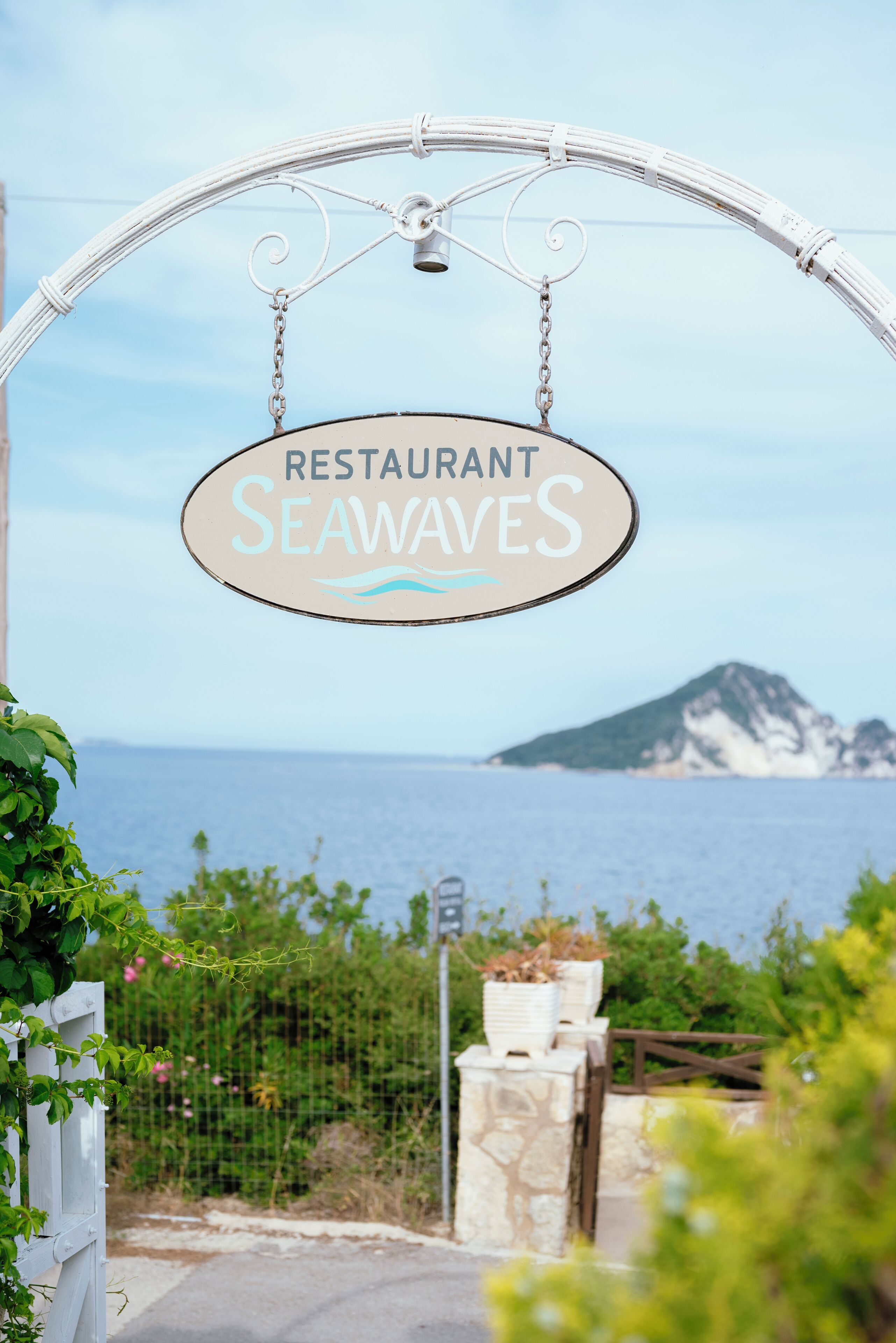 Een bord met de naam 'RESTAURANT SEAWAVES' dat boven een poort hangt.