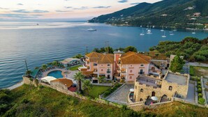 A coastal hotel with a pool, outdoor seating, and views of the sea and boats. - Harmony Hotel (Zakynthos)