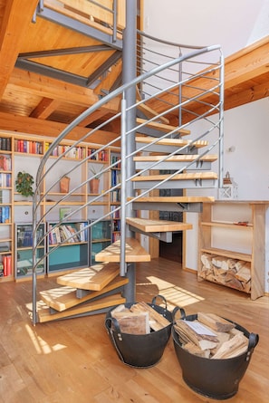 Eine Wendeltreppe mit Holzbodenstufen und Metallgeländern, umgeben von Bücherregalen und einem Kamin.