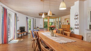 Un comedor amplio con una larga mesa de madera, múltiples sillas e iluminación colgante.