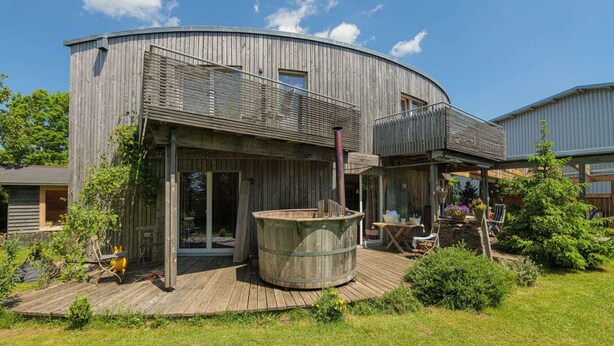 Una casa de madera rústica con un amplio balcón, un jacuzzi y asientos al aire libre.