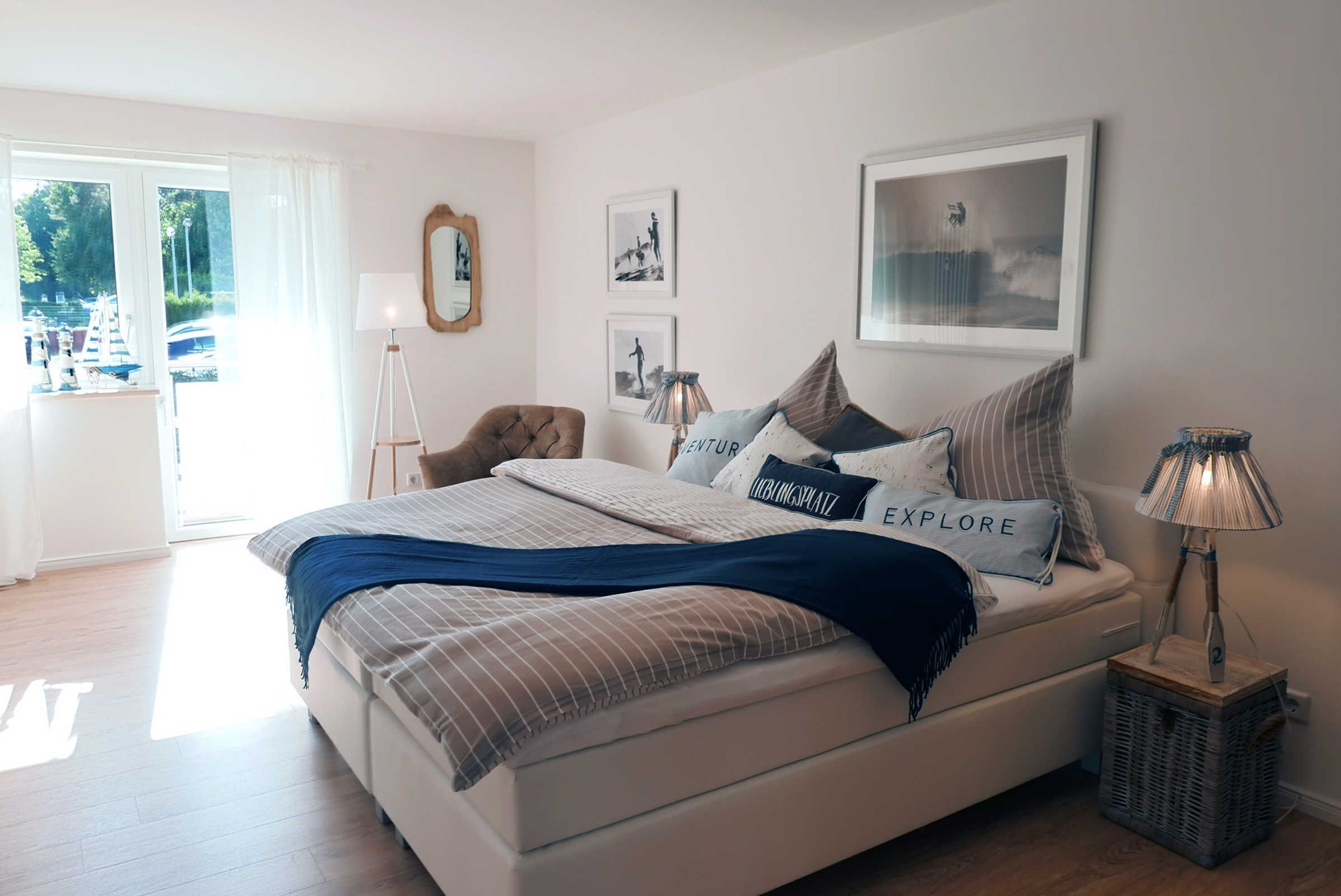 Une chambre à coucher avec un lit, une lampe, un miroir et des tableaux encadrés accrochés au mur.