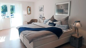 Een slaapkamer met een bed, een lamp, een spiegel en foto's in lijsten aan de muur.