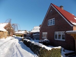 A residential street with snow-covered houses and a clear blue sky.