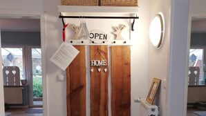 A home entryway with a wooden panel wall, a bench, a welcome mat, and a sign that says 'OPEN'.