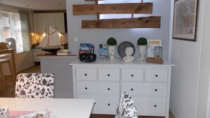 A dining area with a white table, patterned chairs, a white cabinet with drawers, and a wooden wall decoration.