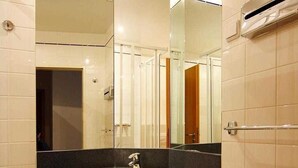 Un baño con lavamanos, espejo y toallero.