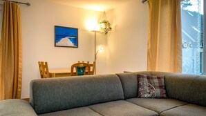 Una sala de estar moderna con un sofá gris, una mesa de comedor de madera y un cuadro colgado en la pared.