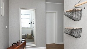 A hallway with a wooden bench, a mirror, and two wall-mounted baskets. - Vacation apartment Deichkrone (Wittmund)