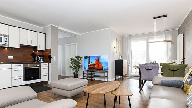 A modern living room with a sofa, a coffee table, and a TV. - Vacation apartment Deichkrone (Wittmund)