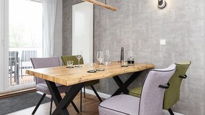 A dining area with a wooden table, four chairs, and a modern pendant light. - Vacation apartment Deichkrone (Wittmund)