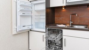 A compact kitchen with a built-in microwave, a dishwasher, and a sink. - Vacation apartment Deichkrone (Wittmund)