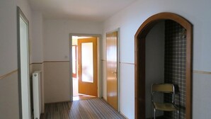 A hallway with a carpeted floor, a door at the end, and a chair in the corner. - Ferienwohnung bis 5 Personen (ca. 90 qm) (Kiefersfelden)