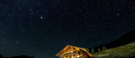 A two-story building with balconies, a parking area, and a starry night sky.