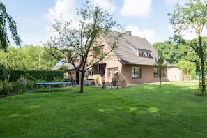 A two-story house with a sloped roof, a visible chimney, and a well-maintained lawn.