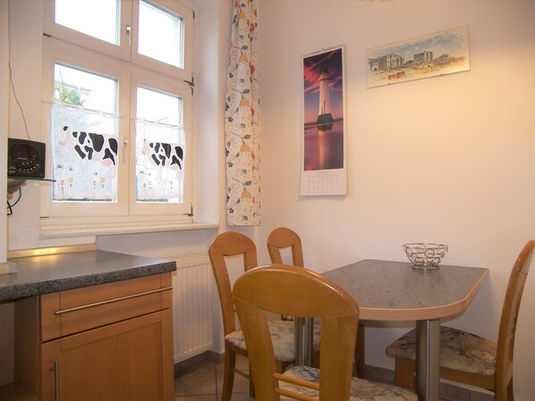 Un comedor con mesa y sillas, una ventana decorada con una vaca y un calendario en la pared.