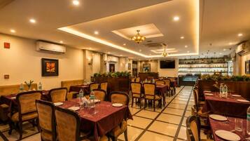 A restaurant with multiple tables and chairs, a bar area, and a ceiling with recessed lighting.