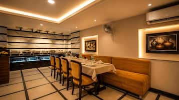 A dining area with a buffet, a sofa, and wall-mounted artwork.