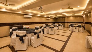 Un salón de conferencias con mesas y sillas redondas, ventiladores de techo e iluminación empotrada.