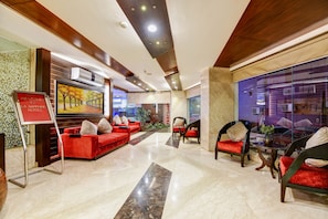 A hotel lobby with red sofas, a glass wall, and a sign that reads 'WE COME TO LA SAPPHIRE HOTEL.' - La-Sapphire Hotel (New Delhi)