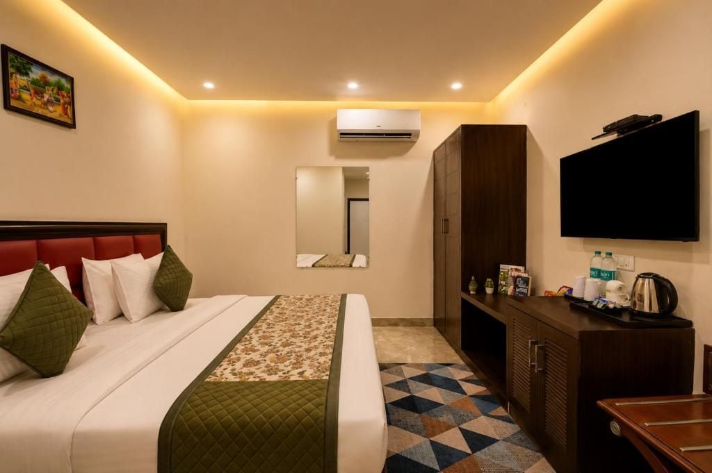 A hotel room with a bed, a TV, a wardrobe, and a mirror.
