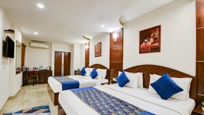 A hotel room with two beds, a desk, a TV, and a painting on the wall. - La-Sapphire Hotel (New Delhi)