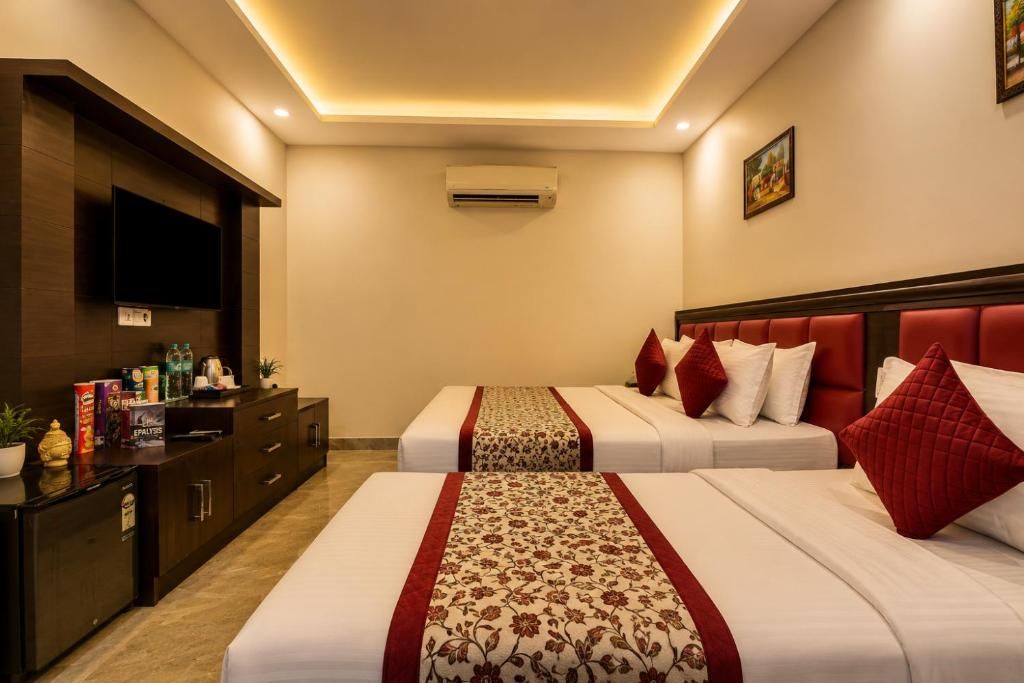 Una habitación de hotel con dos camas, televisor, minibar y aire acondicionado.