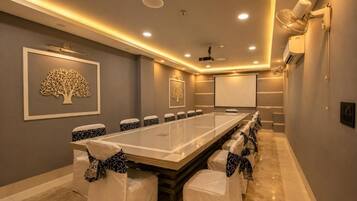 A conference room with a long table, chairs, a projector screen, and a whiteboard.