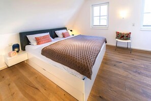 Relax in this serene bedroom with a large bed, side table, and comfortable chair.