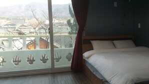 A bedroom with a large window, a bed, and a view of traditional buildings. - Sajo Resort Gyeongju (Gyeongju)