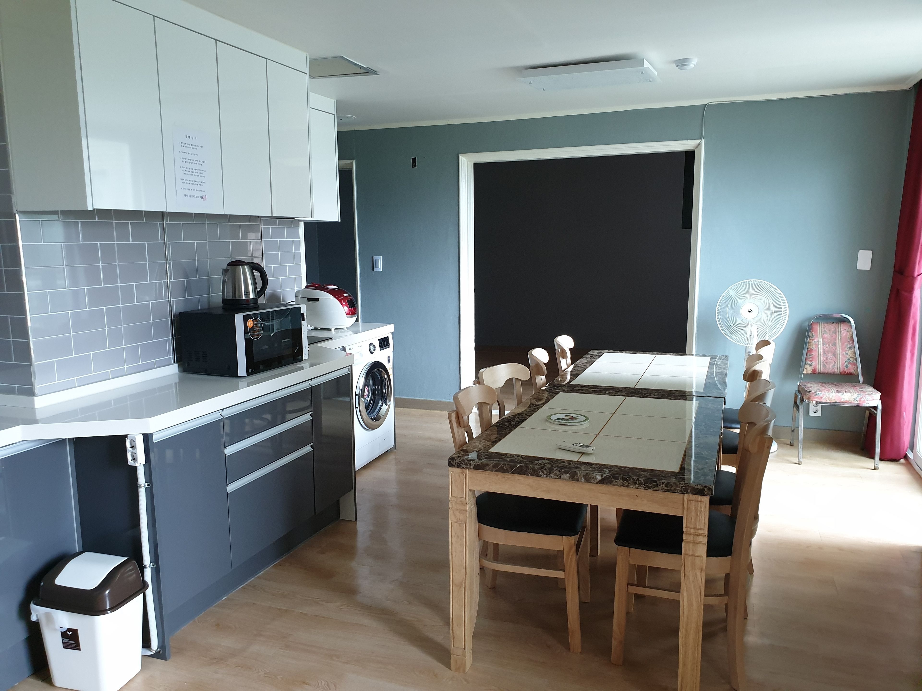 Cocina compacta con lavadora, microondas y comedor con mesa y sillas.