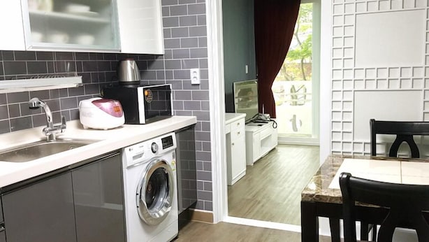 A compact kitchen with a washing machine, a coffee maker, and a dining area with a table and chairs. - Sajo Resort Gyeongju (Gyeongju)