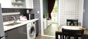 A compact kitchen with a washing machine, a coffee maker, and a dining area with a table and chairs. - Sajo Resort Gyeongju (Gyeongju)