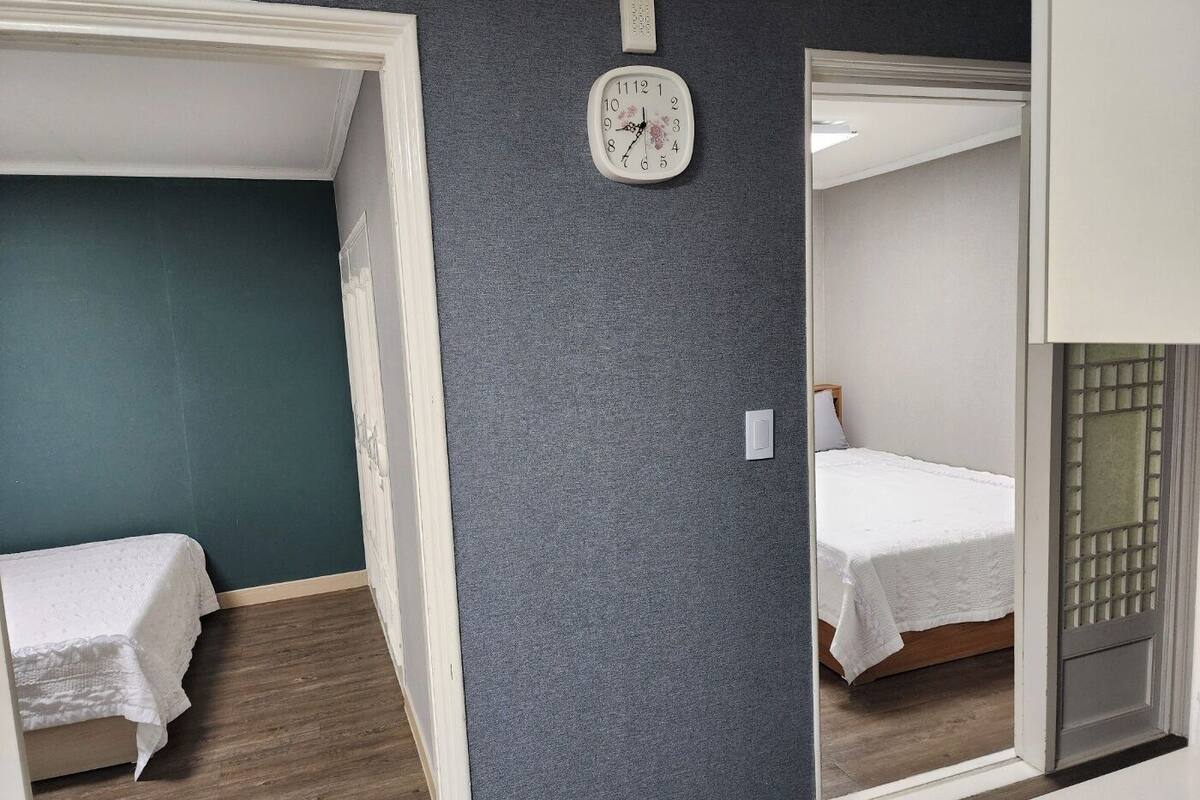 A bedroom with a bed, a wall clock, and a door with a frosted glass panel.