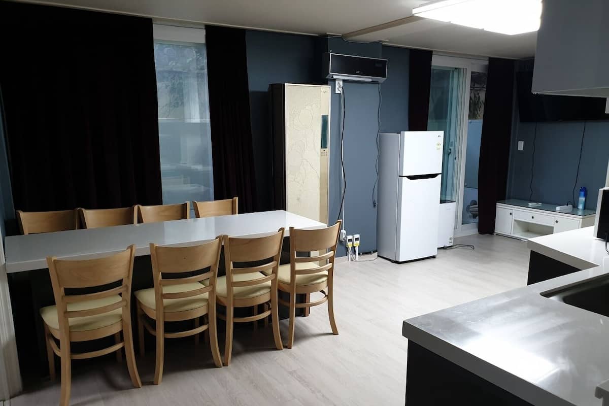 A modern kitchen with a dining table, chairs, a refrigerator, and a microwave.