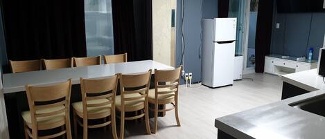A modern kitchen with a dining table, chairs, a refrigerator, and a microwave.
